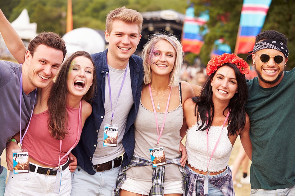 Happy young people at an outdoor festival, wearing lanyards with badges